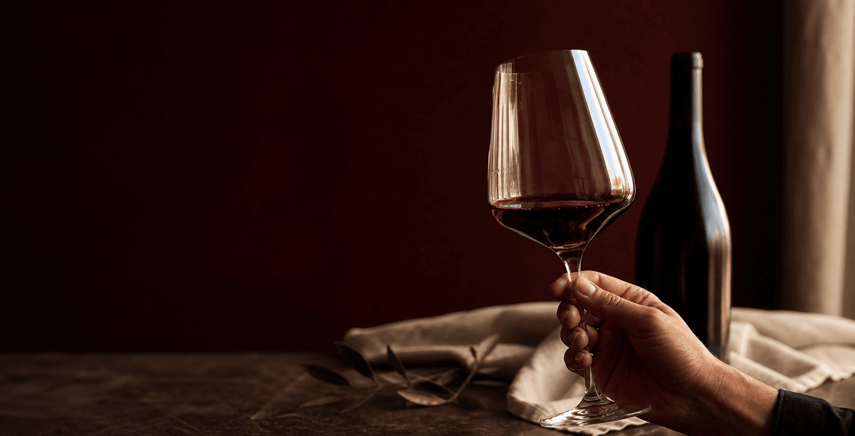 Copa de vino sostenida por el tallo en una mesa de degustación
